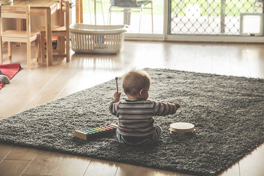 baby playing in the room on the grey carpet