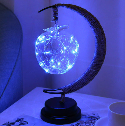 Apple hanging from a moon shaped night lamp