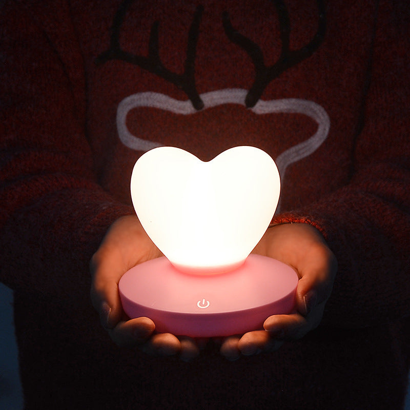 a human holding with both hands heart shaped night lamp