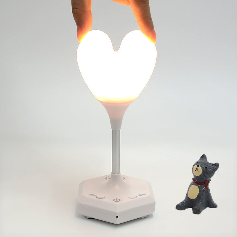 white heart shaped night lamp held by humans two fingers