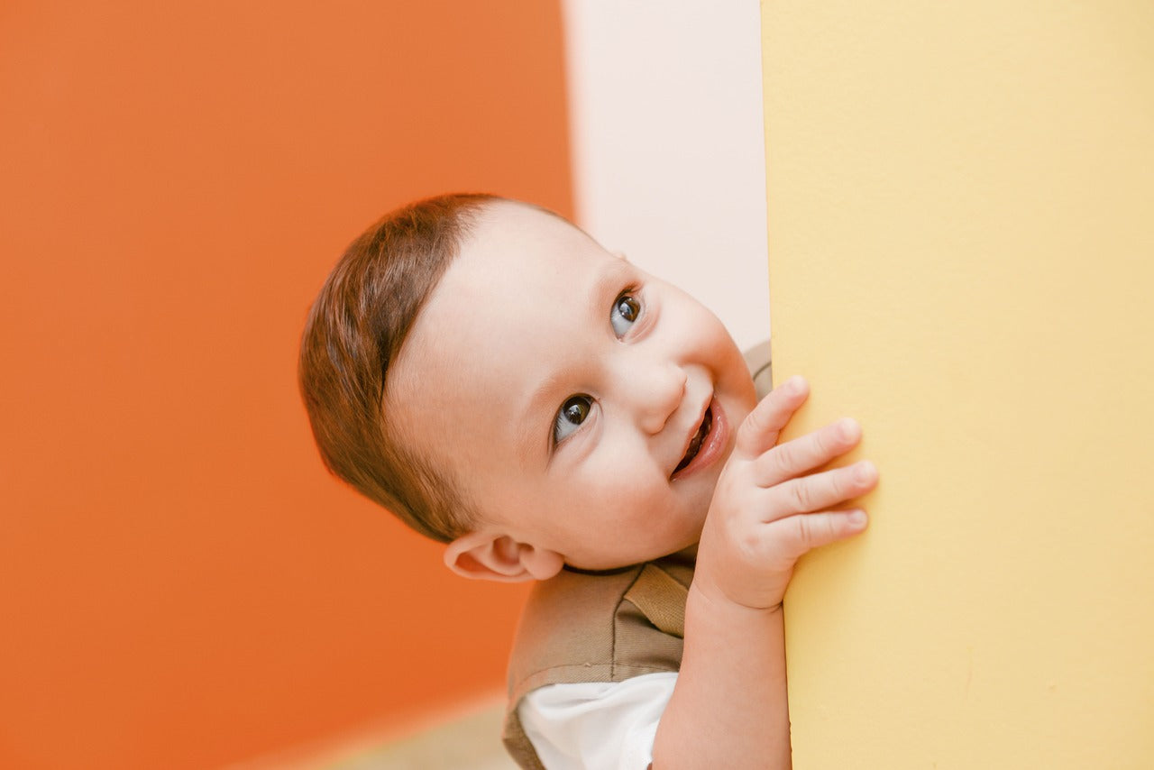 a little boy glancing out of the corner of the wall