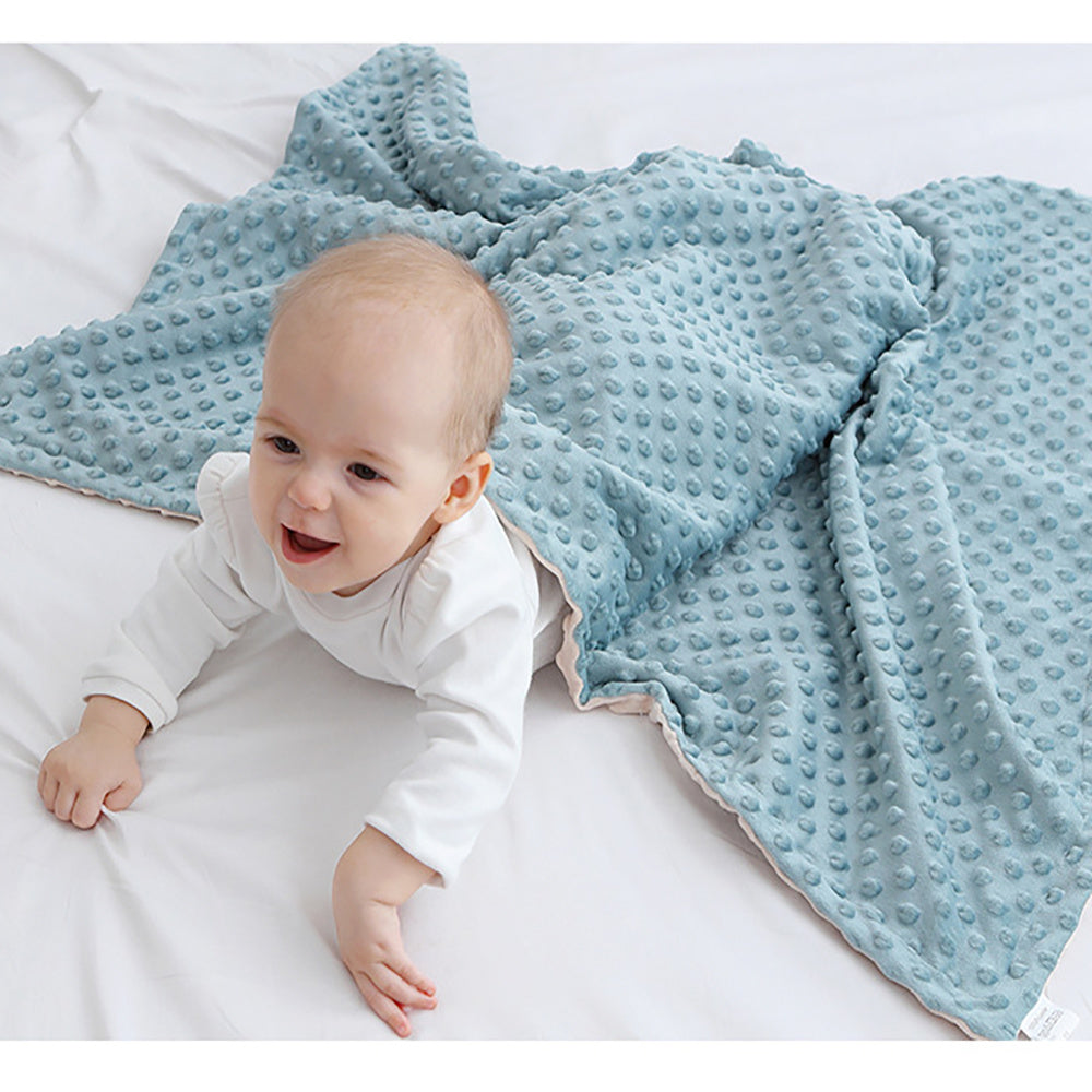 a smiling baby under a blue comfort blanket
