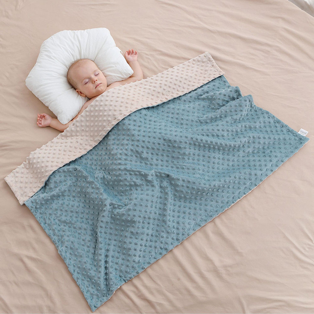 baby sleeping on the pink sheets with a blue baby blanket covering