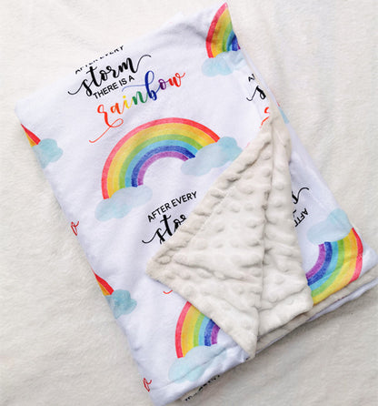 Folded with one corner unfolded baby blanket with rainbows